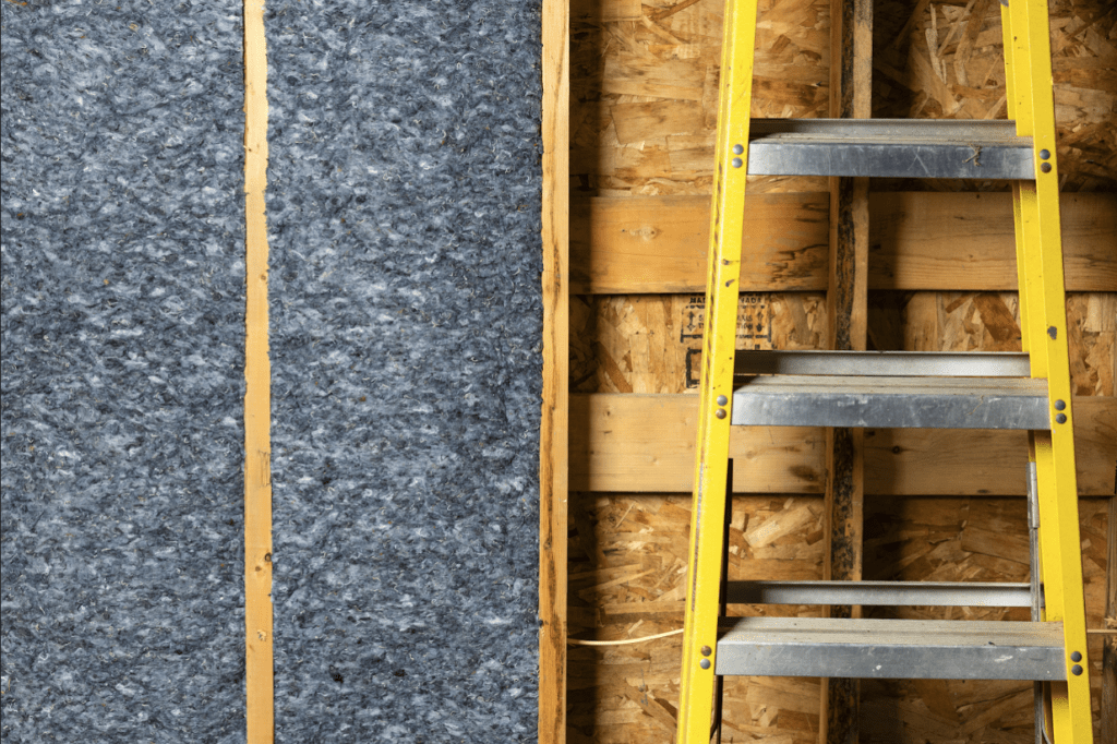 An image of Quiet Denim insulation and a ladder against a framed wall. 
