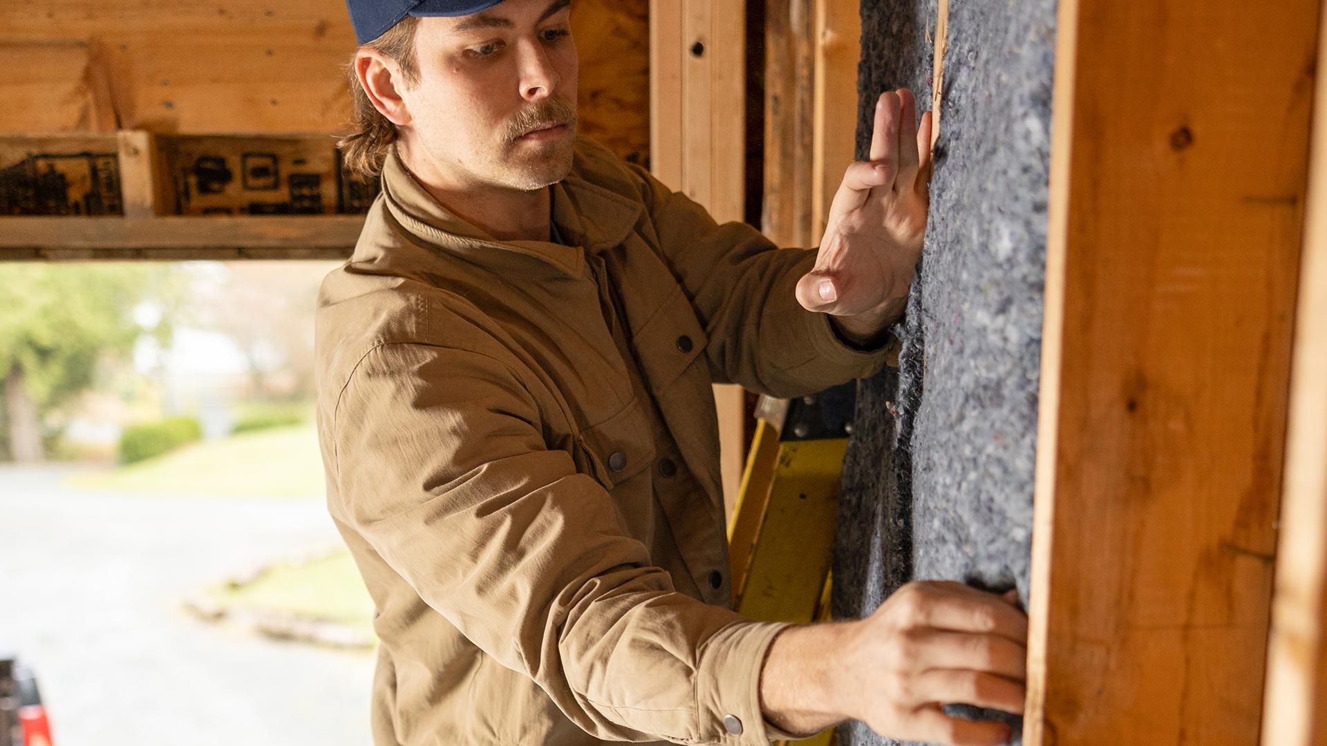 Man Installing Quiet Denim into a Wall Cavity