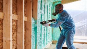 Spray foam repair in progress as a worker applies foam insulation to exposed framing.