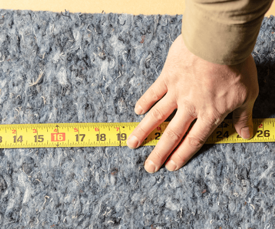 Close up of Quiet Denim insulation being measured to ensure a proper fit.