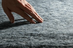 Close-up of a hand touching recycled denim insulation material.