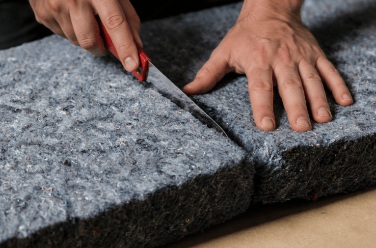 Installer cutting recycled denim insulation batt to size for a custom wall cavity fit. 